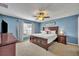 Cozy main bedroom with a dark wood bed frame, plush carpeting, and a ceiling fan at 3642 Doe Run Dr, St Cloud, FL 34772