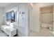 Hallway with TV, cabinet and entry to bathroom with white tile floors and wall-mounted light fixture at 417 Noble Ave, Davenport, FL 33837