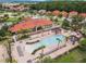 Aerial view of community clubhouse with a large pool, surrounded by lounge chairs, umbrellas, and palm trees at 4506 Alberto Cir, Kissimmee, FL 34746