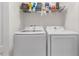 Well-organized laundry room with washer, dryer, and overhead shelving for storage and organization at 4846 Coral Castle Dr, Kissimmee, FL 34746