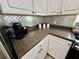 A kitchen view showcases brown counter tops with white cabinets and stainless steel backsplash at 650 Tuscan Hills Blvd, Davenport, FL 33897