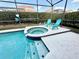 Screened pool area featuring a pool with an integrated spa and two turquoise chairs at 650 Tuscan Hills Blvd, Davenport, FL 33897