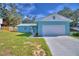 A beautiful home features a metal roof, blue exterior, attached one car garage, and manicured lawn at 713 Greenleaf Ln, Lake Wales, FL 33853