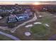 Aerial view showcasing luxury homes adjacent to a golf course with a beautiful sunset at 7471 Gathering Loop, Reunion, FL 34747