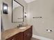 Powder room with dark wood cabinets, granite counter, decorative wall lighting and large mirror at 7471 Gathering Loop, Reunion, FL 34747