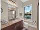 Bathroom featuring granite counters, wooden cabinets and a large window with green outdoor views at 7471 Gathering Loop, Reunion, FL 34747