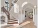 Grand foyer with a curved staircase and arched windows creating a bright, welcoming entrance at 7471 Gathering Loop, Reunion, FL 34747