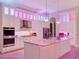 Modern kitchen featuring white cabinets, an island with lights, and colorful lighting at 7471 Gathering Loop, Reunion, FL 34747