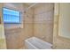 Bathroom with shower and tub combination featuring decorative tile and window offering natural light at 105 Shaddock Dr, Auburndale, FL 33823