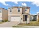 Two-story home featuring a two-car garage, blue front door, well-manicured lawn, and tasteful landscaping at 1368 Berry Ln, Davenport, FL 33837