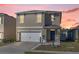 Two-story home featuring a two-car garage, blue front door, well-manicured lawn, and tasteful landscaping at 1368 Berry Ln, Davenport, FL 33837