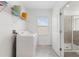 Bright laundry room with a white washer and dryer, shelving, gray tile flooring, and a door to a tiled shower at 139 Aces High Ln, Davenport, FL 33896