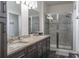 Bathroom featuring a glass shower, double sinks with granite countertops, and updated fixtures at 2038 Lily Pl, Kissimmee, FL 34759