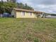 View of house with metal roof, charming shutters, and a spacious, slightly overgrown front yard at 2227 Virginia Dr, Kissimmee, FL 34741