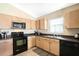 Kitchen with light wood cabinets, modern appliances, and a window for natural light at 226 Bailey Cir, Davenport, FL 33897