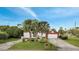 Exterior view of a white home with a red garage, surrounded by palm trees and green grass, under a clear blue sky at 2462 Albany Dr, Kissimmee, FL 34758