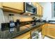 Close up of a kitchen with wood cabinets, stainless steel appliances, and dark countertops at 2725 Coupe St, Kissimmee, FL 34746