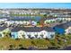 An aerial view of colorful townhomes bordering a scenic lake in a vibrant community at 2980 Caribbean Soul Dr, Kissimmee, FL 34747