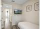 Cozy bedroom with neutral walls, a mounted TV, and natural light from the hallway's end window at 2980 Caribbean Soul Dr, Kissimmee, FL 34747