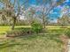 Manicured backyard featuring lush green grass, mature trees with Spanish moss, and tasteful landscaping at 328 Hamrick Dr, Kissimmee, FL 34759