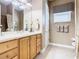 Bright bathroom features a wooden vanity, a mirror, and neutral-toned walls and tiling at 328 Hamrick Dr, Kissimmee, FL 34759