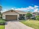 Lovely single-story house features a manicured lawn, a brick-paved driveway, and an attached two-car garage at 328 Hamrick Dr, Kissimmee, FL 34759