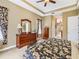 Spacious main bedroom featuring tray ceilings, a ceiling fan, and a wooden dresser with a large mirror at 328 Hamrick Dr, Kissimmee, FL 34759