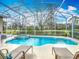 Sparkling screened pool and spa overlooking serene backyard views at 328 Hamrick Dr, Kissimmee, FL 34759