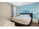 A tranquil bedroom with bright blue walls, plush bedding and decorative lamps for a peaceful and stylish getaway at 430 Novi Path, Kissimmee, FL 34747