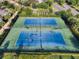 Aerial view of well-maintained tennis courts surrounded by lush greenery and landscaping at 430 Novi Path, Kissimmee, FL 34747