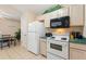 Kitchen area features white appliances and cabinetry with view into dining area at 446 Reserve Dr, Davenport, FL 33896