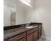 Bathroom with dark granite countertops, a large mirror, and a shower with mosaic tile at 4774 Rummell Rd, St Cloud, FL 34771