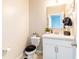 Cozy half bathroom featuring modern vanity, mirror, and toilet with decorative seat cover at 4823 Coral Castle Dr, Kissimmee, FL 34746