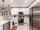 Modern kitchen featuring stainless steel appliances, white cabinetry, and stylish pendant lighting at 4823 Coral Castle Dr, Kissimmee, FL 34746