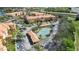 Aerial view of a condo complex with amenities, including a tennis court, pool, and parking at 5463 Vineland Rd # 5107, Orlando, FL 32811