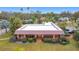 Brick home featuring a low-pitch metal roof, a brick-paved front porch, and manicured lawns at 6 Palm Way, Haines City, FL 33844