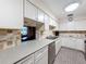 Bright kitchen with white cabinets, stainless appliances, and views of the backyard through a passthrough window at 6 Palm Way, Haines City, FL 33844