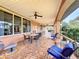 Covered brick patio with ample seating, ceiling fans, and views of the lush landscaping at 6 Palm Way, Haines City, FL 33844