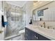 Elegant bathroom with a glass shower featuring marbled walls, navy vanity, and gold fixtures at 651 Glendora Rd, Kissimmee, FL 34759