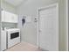 Laundry room with white cabinetry and machines, plus practical tile flooring and door at 651 Glendora Rd, Kissimmee, FL 34759