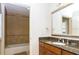 Bathroom with tiled shower-tub combo, granite vanity, large mirror, and neutral decor at 7660 Whisper Way # 104, Reunion, FL 34747