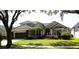 Charming one-story home features lush landscaping, a well-manicured lawn, and a tile roof at 7670 Milano Dr, Orlando, FL 32835