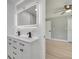 Modern bathroom with a double sink vanity, illuminated mirror, and view to the light and airy bedroom at 7904 Empire Ave, Orlando, FL 32810