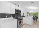 Well-lit kitchen featuring sleek black backsplash, modern appliances, and ample white cabinetry for storage at 816 Garden Glen Loop, Lake Mary, FL 32746