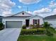 Charming one-story home with a gray garage door, red window shutter, and stone facade at 1042 Heirloom Dr, Haines City, FL 33844