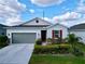 Charming one-story home with a gray garage door, red window shutter, and stone facade at 1042 Heirloom Dr, Haines City, FL 33844