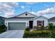Inviting single-story home with a gray garage door, stone accents, and a lush, landscaped front yard at 1042 Heirloom Dr, Haines City, FL 33844