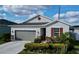 Inviting single-story home featuring a gray garage door, stone accents, and a lush, landscaped front yard at 1042 Heirloom Dr, Haines City, FL 33844