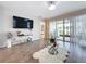 Open living room featuring tile floors, a large television, and access to an outdoor patio at 1042 Heirloom Dr, Haines City, FL 33844