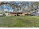 Charming home exterior with screened porch and well-maintained lawn, set among mature trees and lush landscaping at 1250 Pecan St, Kissimmee, FL 34744